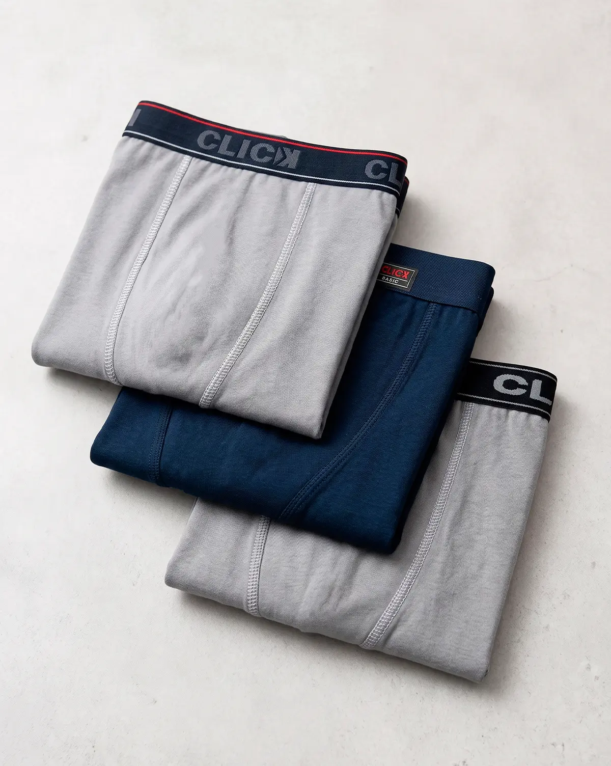 Três cuecas boxer Click dobradas em cinza e azul-marinho